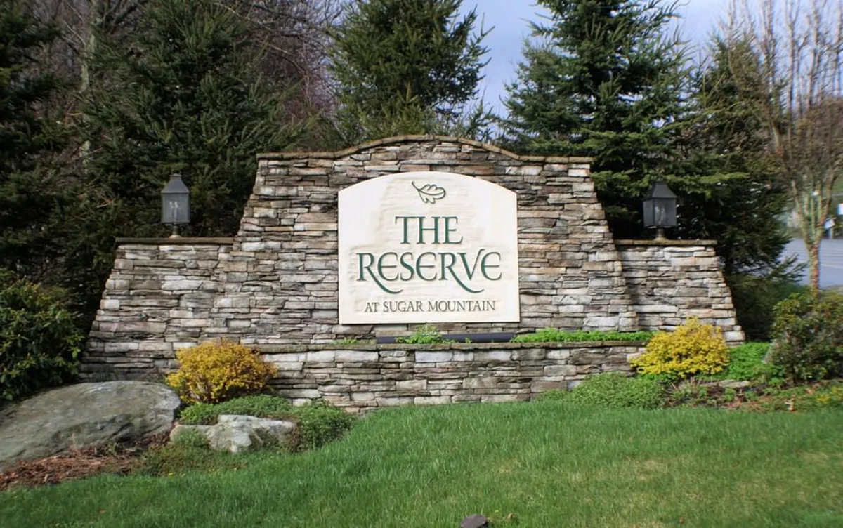 This image shows the exterior stone sign of Heart Rock Lodge surrounded by lush landscaping and tall trees. The inviting entrance is set amidst nature, providing a sense of arrival and hinting at the adventures within.