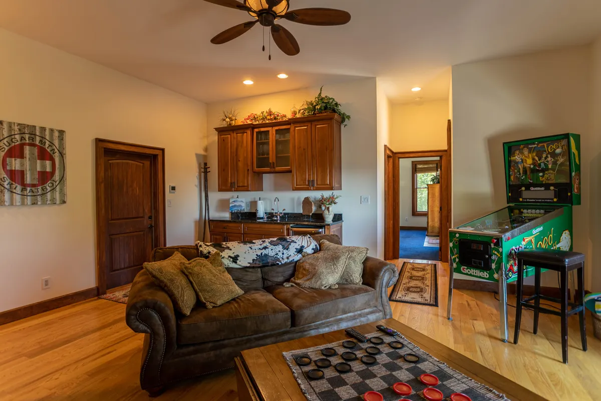 This interior shot centers on a playful lounge area featuring a sofa, a stylish bar, a classic pinball machine, and a dedicated game table. The space radiates a welcoming vibe, inviting guests to engage in social activities, play games, and relax together.