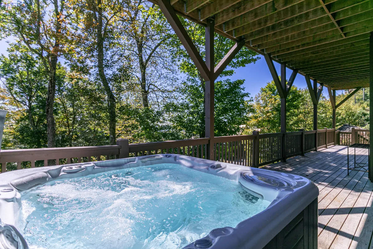 An inviting outdoor deck scene featuring a hot tub surrounded by trees, offering a tranquil spot for relaxation and socializing after a day of excitement. The setting blends nature with comfort.