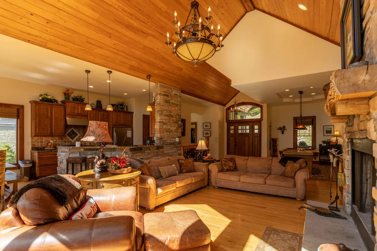 A warm, inviting great room with a central fireplace, plush sofas, and a view into the open kitchen area. The space is perfect for family gatherings, relaxing, or unwinding after a day of outdoor adventures.