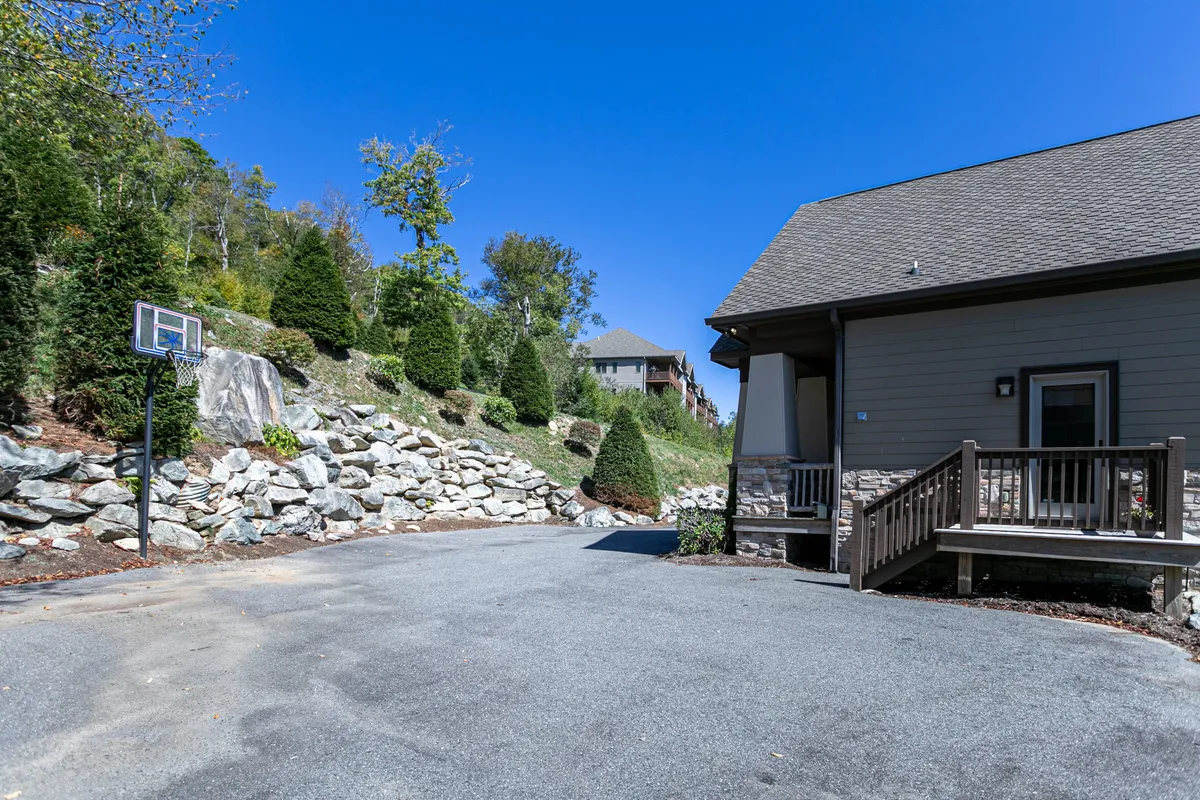 An exterior shot capturing a well-maintained basketball hoop with a rocky landscape and driveway, emphasizing outdoor recreation. The mood is playful and energetic, highlighting possibilities for family-friendly sports and activities.